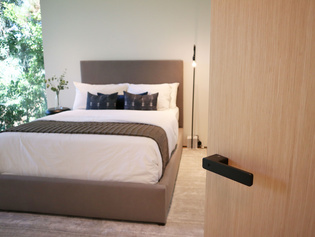 The picture shows the bedroom with a wooden door and door handle R8 ONE in graphite black.