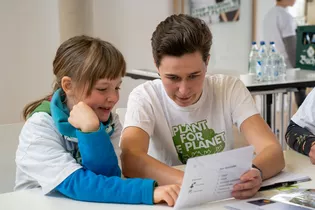 The image shows two people learning about Plant for the Planet.