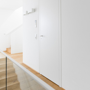 The staircase to the first floor integrates harmoniously without changing the floor material and was only delimited by a transparent glass wall.