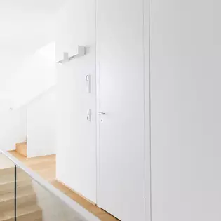 The staircase to the first floor integrates harmoniously without changing the floor material and was only delimited by a transparent glass wall.
