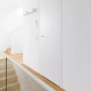 L'escalier menant au premier étage s'intègre harmonieusement sans changer de matériau de sol et a simplement été délimité par une paroi de verre transparente.