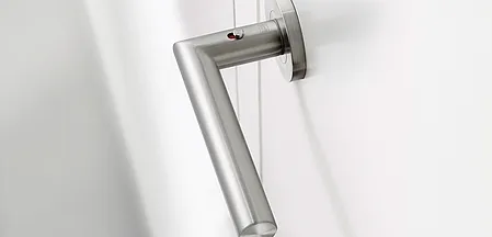 L'illustration montre la poignée de porte Lucia en Acier inox montée sur une porte en bois blanc.