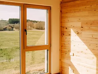 L'illustration montre l'intérieur d'une maison en bois équipée de la Poignée de fenêtre AVUS en Gris cachemire.