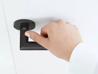 Die Abbildung zeigt den Griffwerk Türgriff Lucia smart2lock in Graphitschwarz mit einer Hand am Griff. Die Hand verschließt den Türgriff am Verriegler.